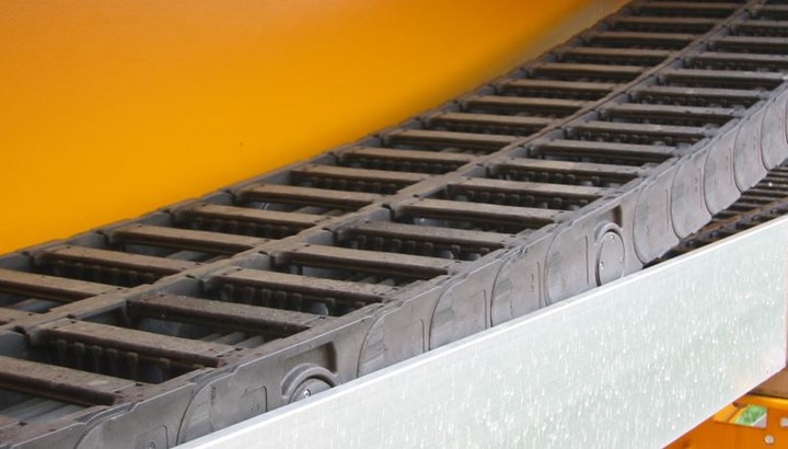 energy chain systems on guide troughs and against orange wall backdrop