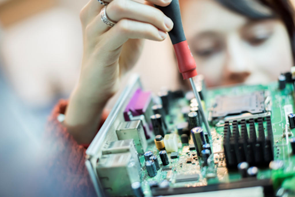 woman using a screwdriver on a computer board