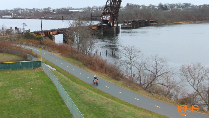 person on the orange igus bike near a bridge and water